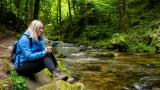 Woman checking phone by a stream