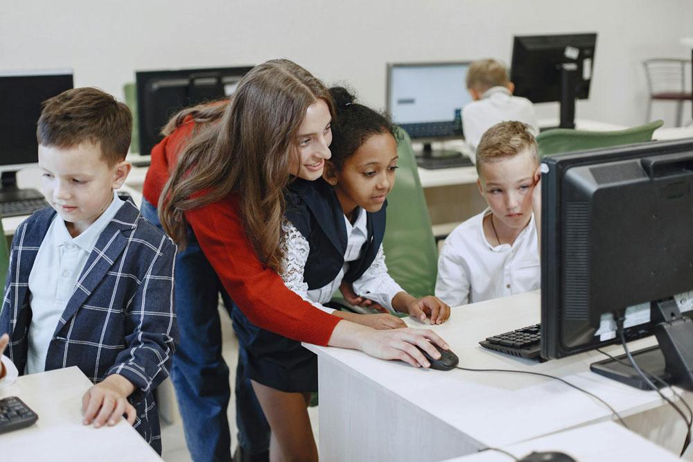Teacher helping students with computers